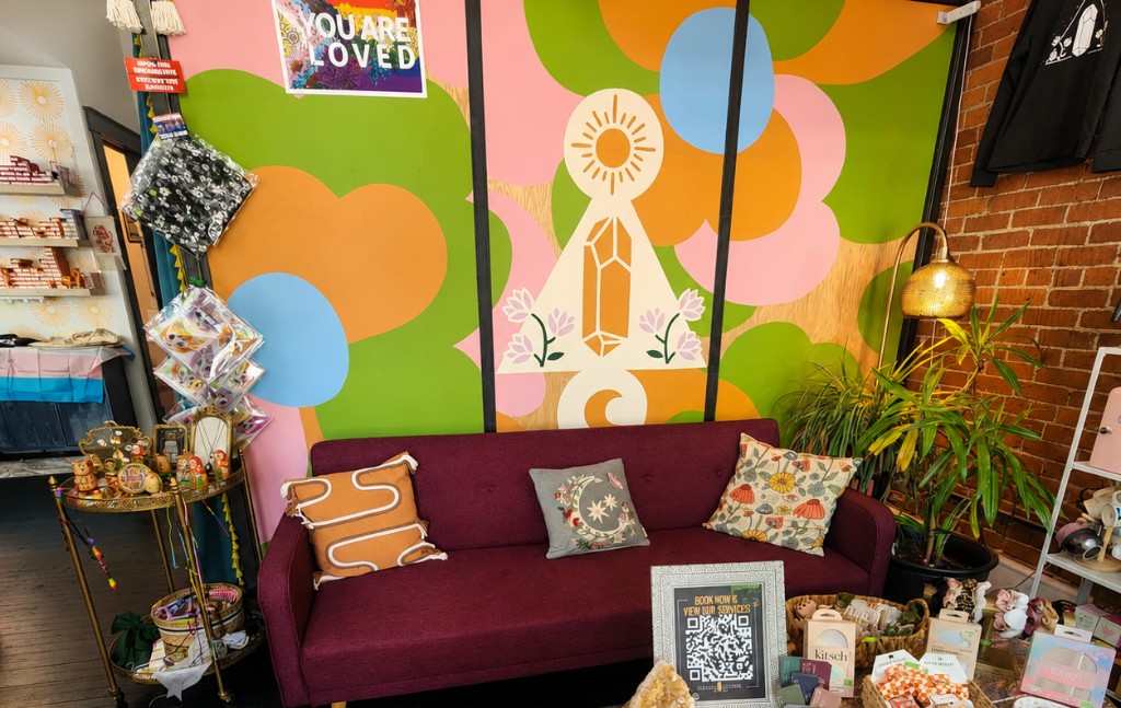 Salon Citrine waiting area with plum sofa, colorful mural, and retail display